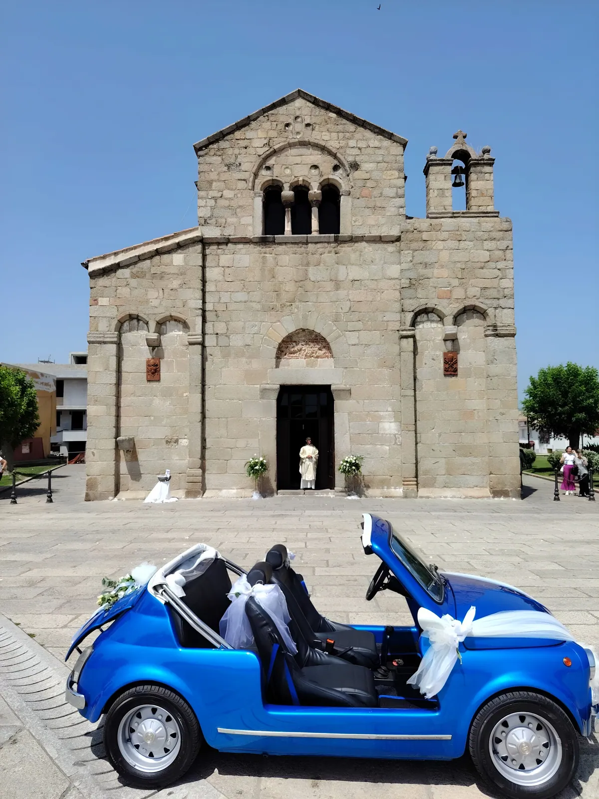 Chiesa in pietra e auto degli sposi decorata