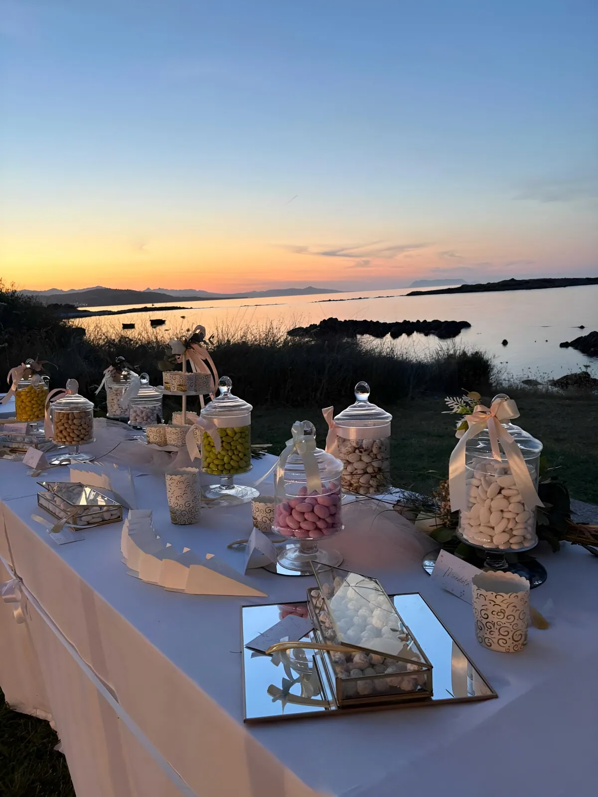 Tavolo dei confetti allestito al tramonto, con il mare e le isole sullo sfondo
